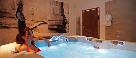 A spa room with a hot tub, a wooden door, and a towel rack.