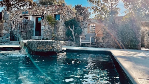 A stone building with a pool, a chair, and a sign that reads "CLIFTON".
