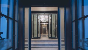 Ein Hotelzugang mit Glastür, einer Kandelaber und einer Treppe zum Innenbereich.