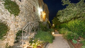 Un bâtiment en pierre avec un chemin de gravier menant à un escalier en bois.