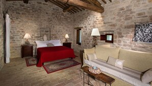 Une pièce aux murs de pierre, avec un lit, un canapé et une table en bois.