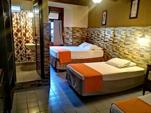 Una habitación de hotel con dos camas, un baño con cortina de ducha y una pared con azulejos.