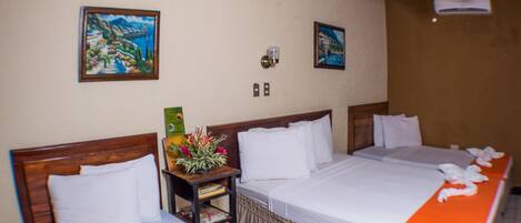 A hotel room with two beds, a ceiling fan, and artwork on the walls.