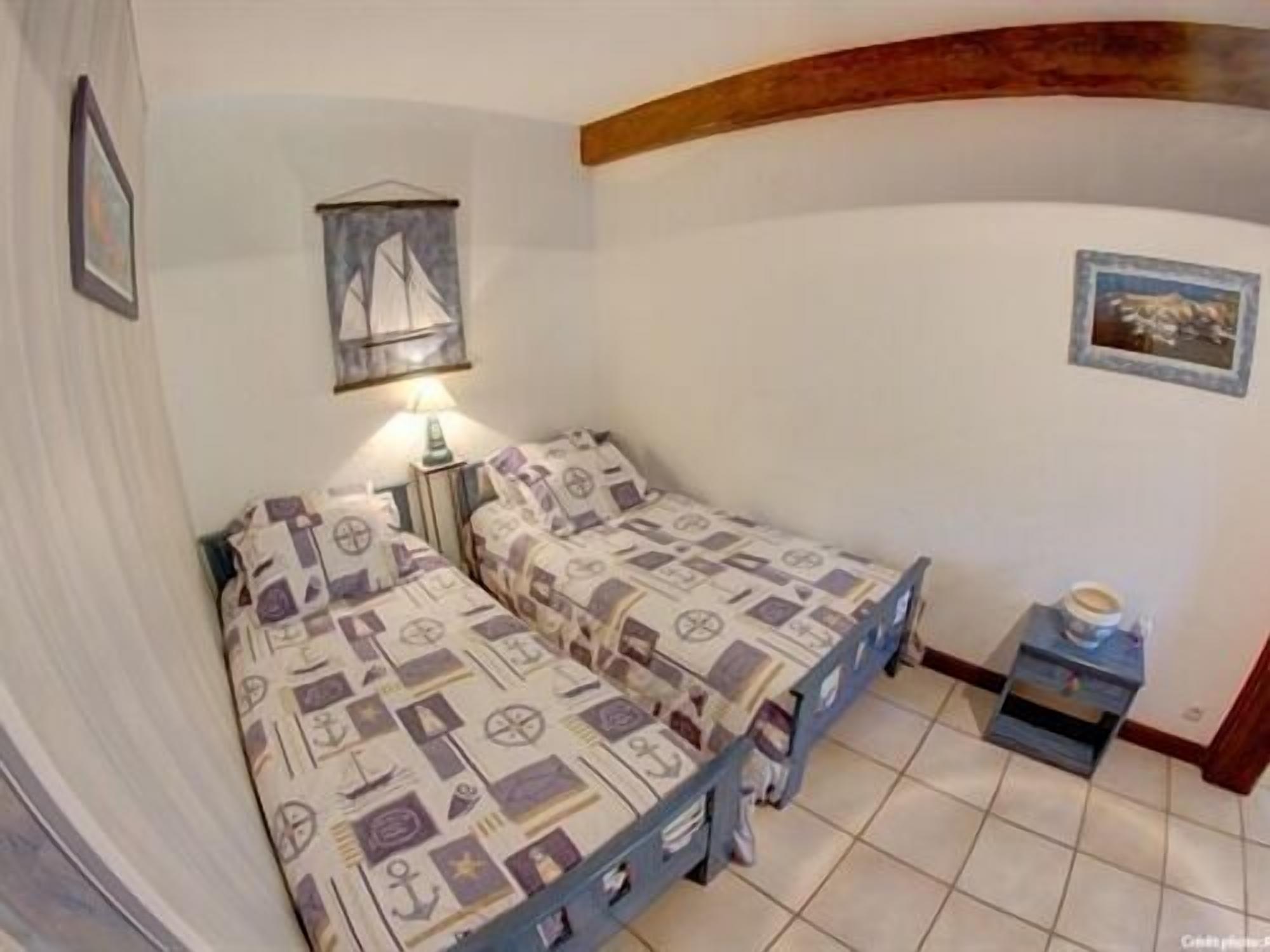 A bedroom with two single beds, a nightstand, a lamp, and a small table with a box.