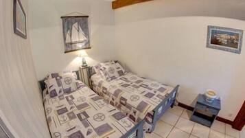 A bedroom with two single beds, a nightstand, a lamp, and a small table with a box.