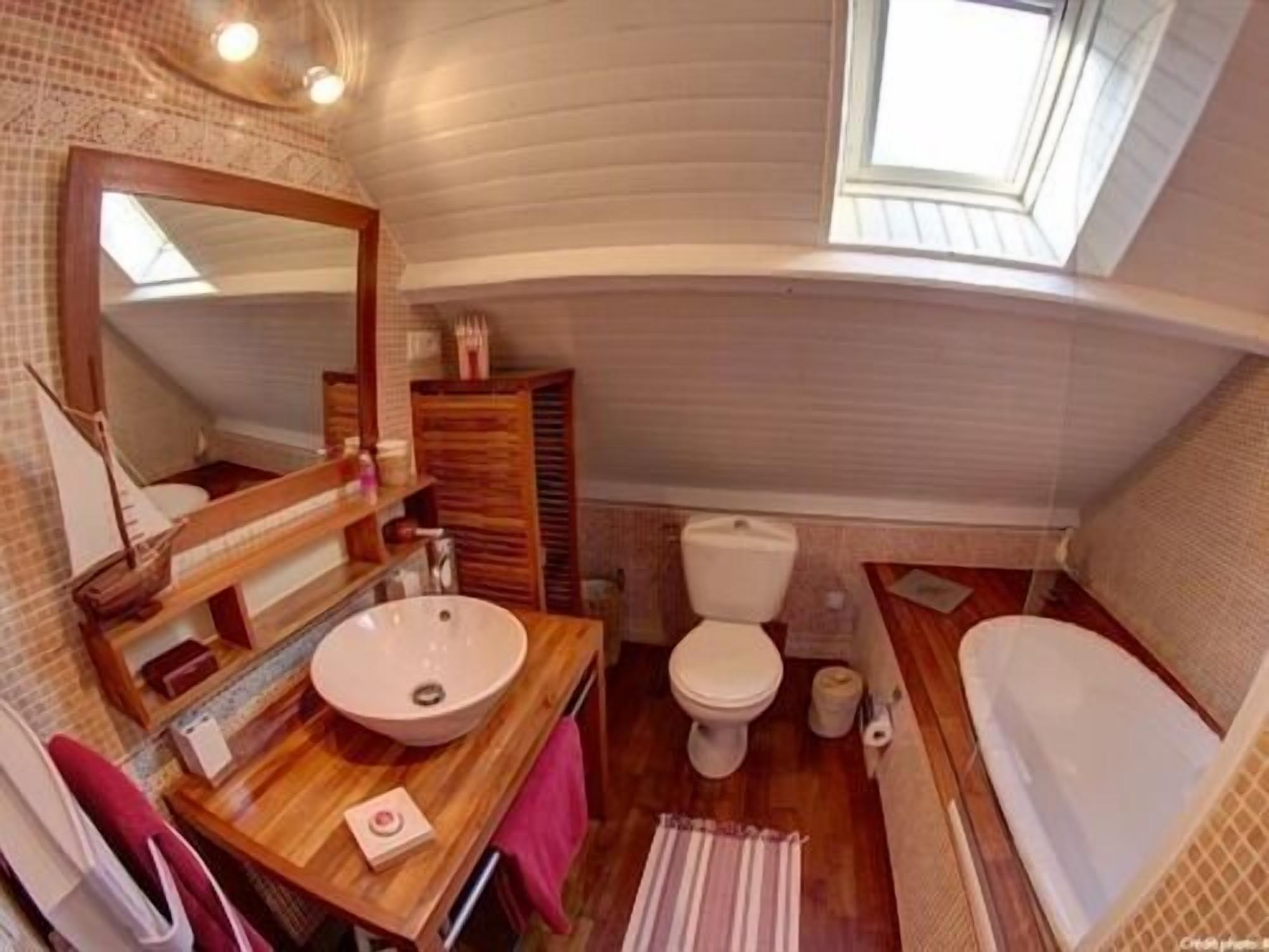 Un baño pequeño con tocador de madera, un lavabo, inodoro y bañera.