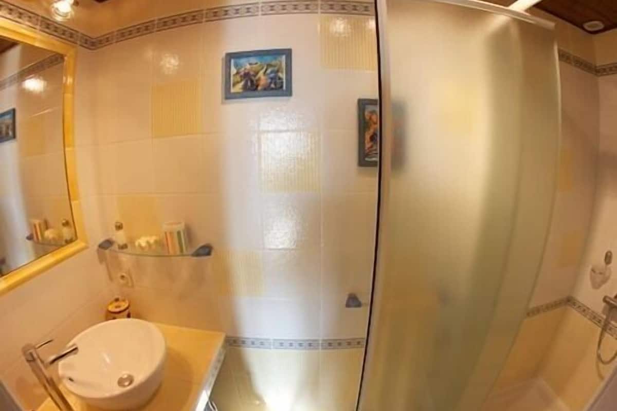 A bathroom with a white sink, a mirror, and a shower enclosure.