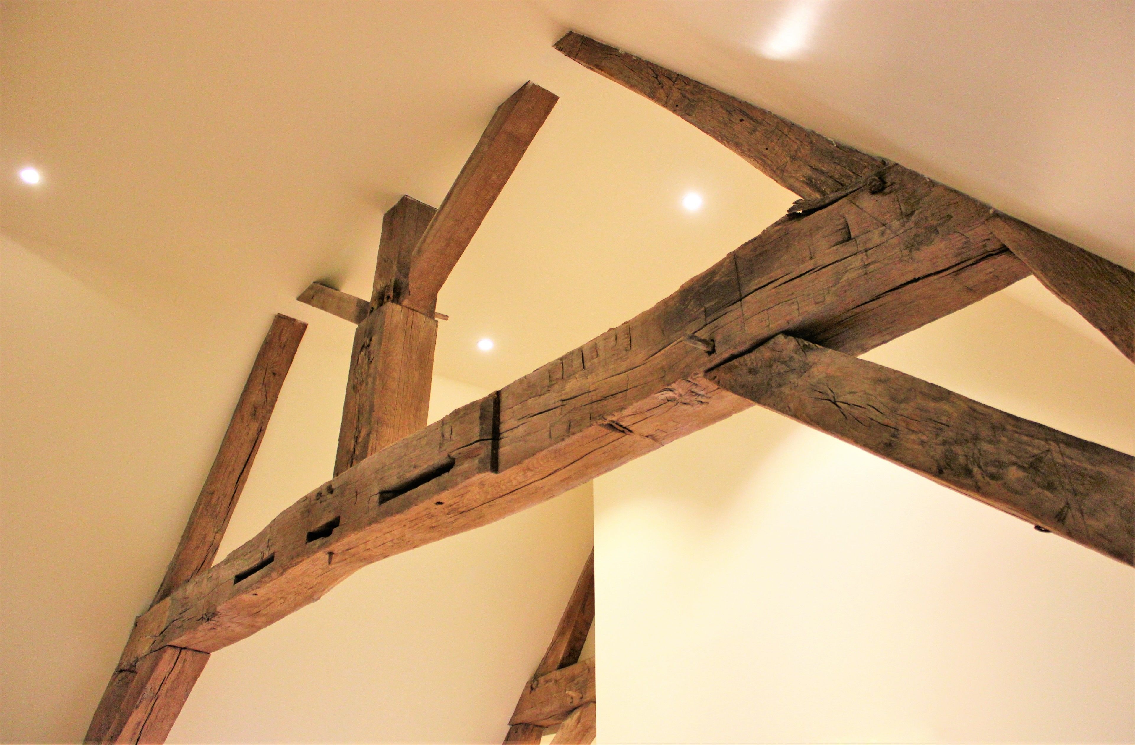 Une structure de plafond en bois avec des poutres et un luminaire encastré.