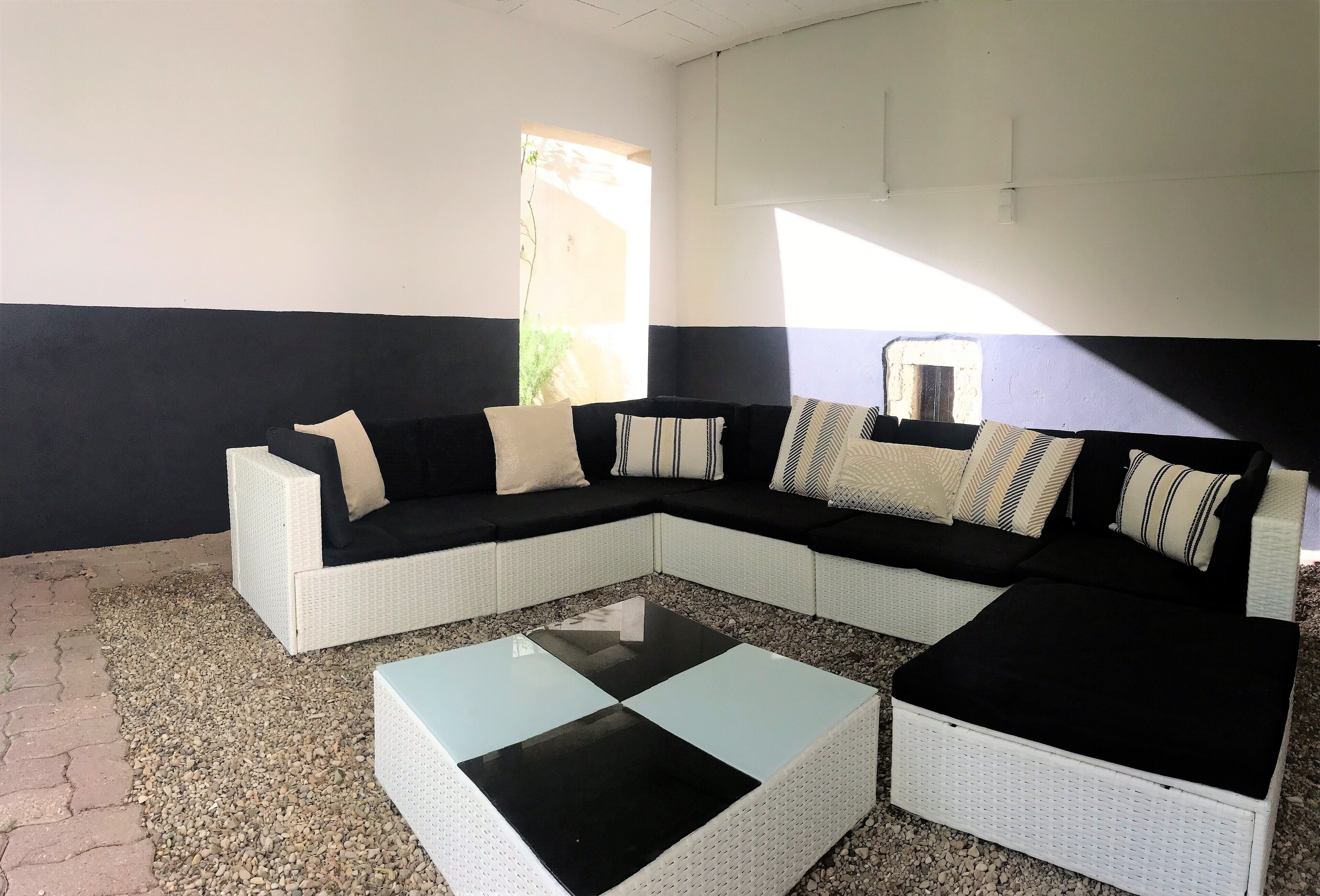 A modern living room with a sectional sofa, a glass coffee table, and a small white table.