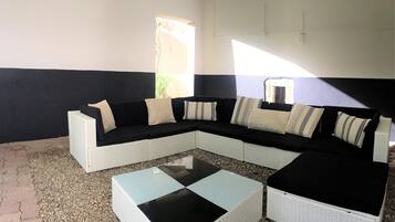 A modern living room with a sectional sofa, a glass coffee table, and a small white table.