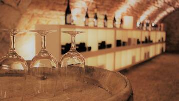 A barrel with three empty wine glasses and a shelf with bottles in the background.
