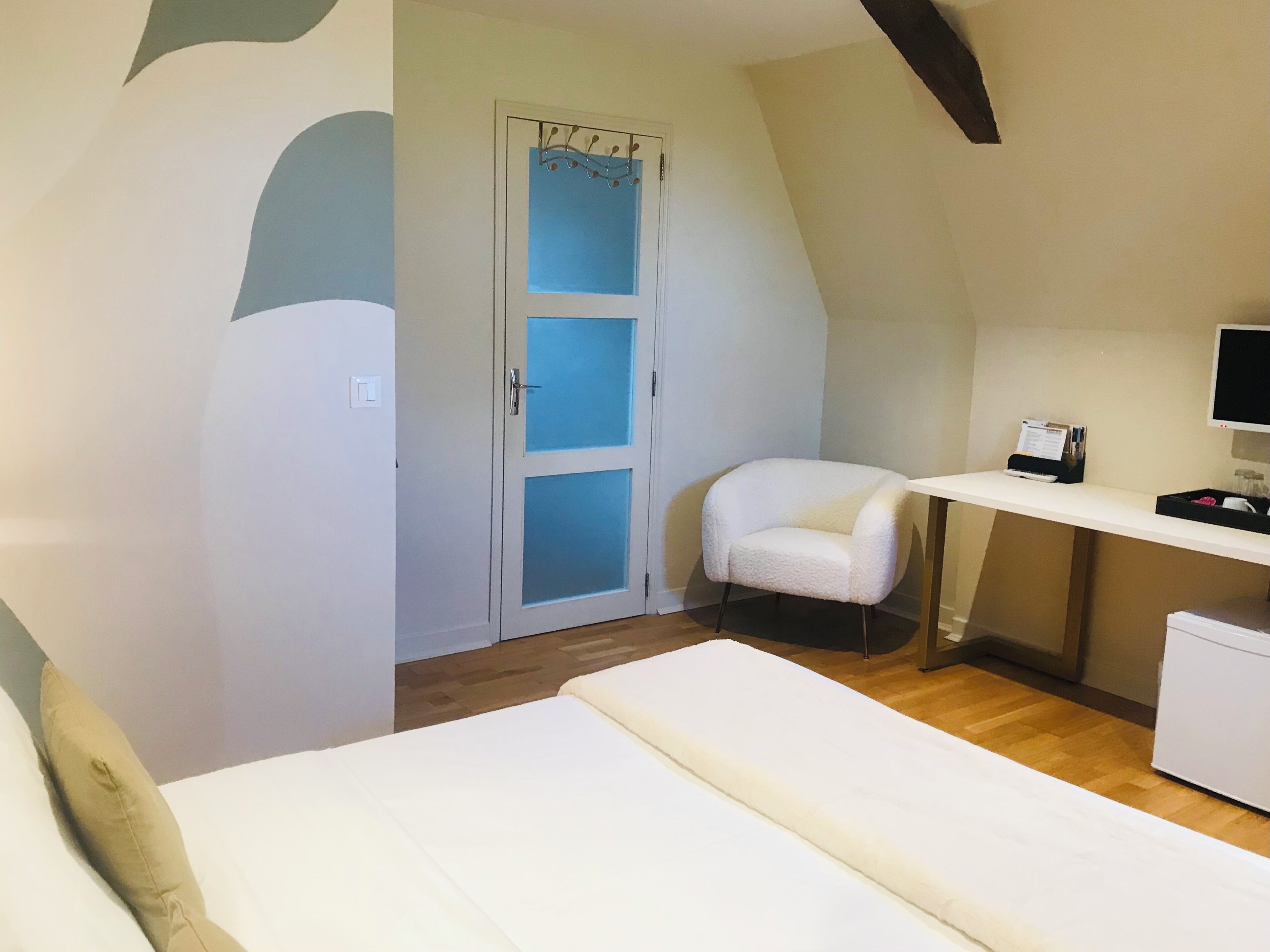 Ein Schlafzimmer mit Bett, Schreibtisch, Stuhl, Kleiderschrank und Fernseher.