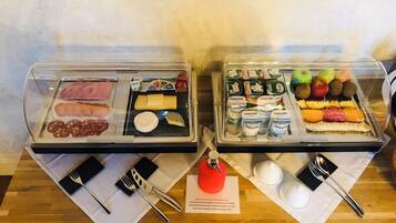 Un buffet proposant une variété de plats, notamment des viandes, des fromages et des fruits.