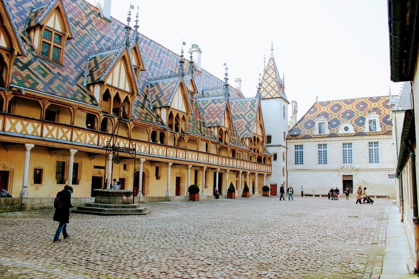 A cobblestone courtyard with historic buildings featuring timber framing and ornate gables.