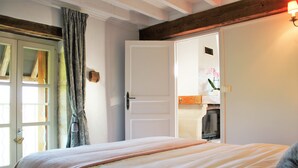 Een slaapkamer met een bed, een deur naar een badkamer en een wandlamp.