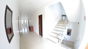 A hallway with a mirror, a staircase, and a door. - Hotel Penha (Penha)