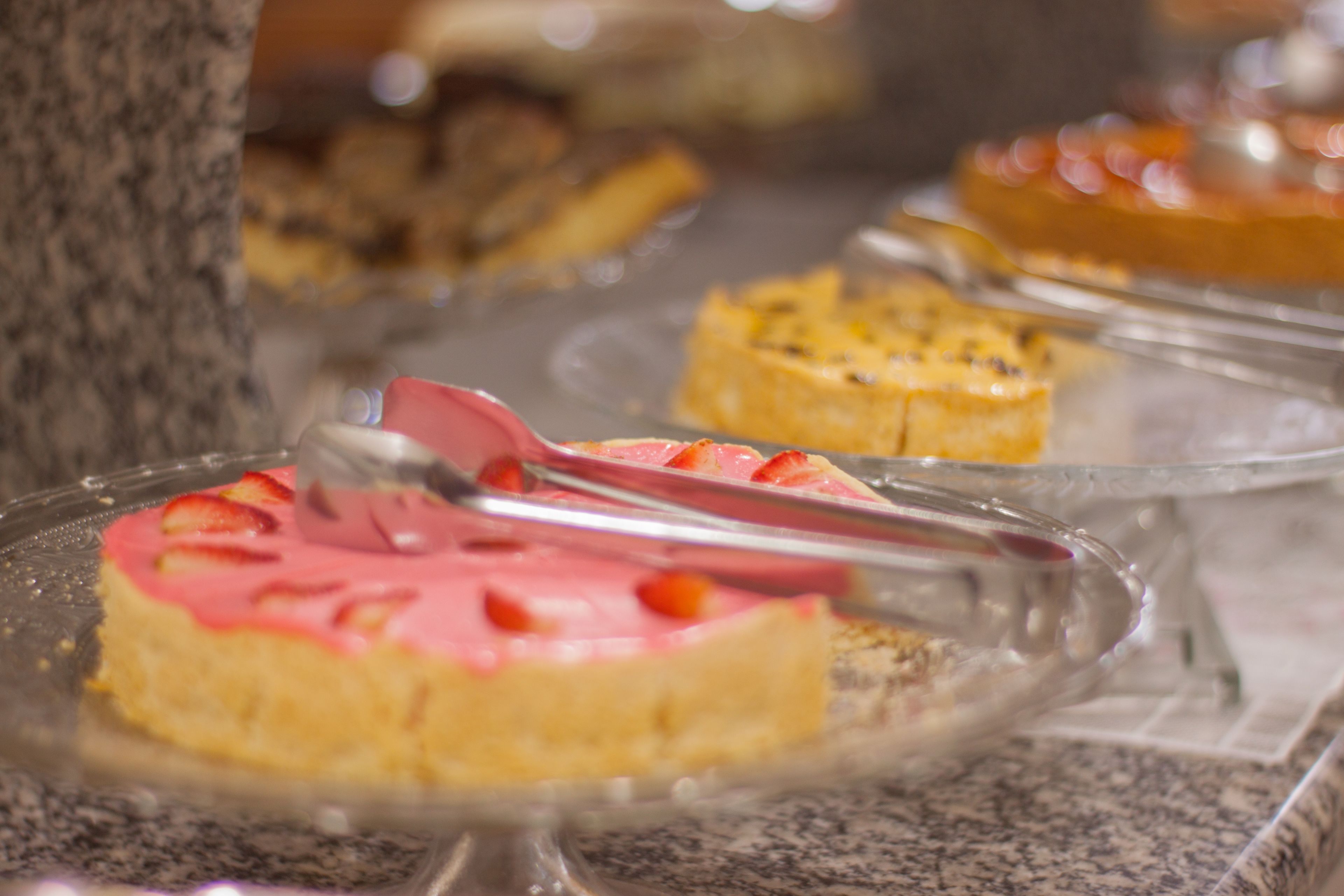 Un aparador de postres amb diferents pastissos i pastisseria sobre plats de vidre transparent.
