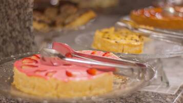 Un aparador de postres amb diferents pastissos i pastisseria sobre plats de vidre transparent.
