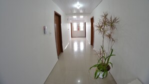 A hallway with white walls, wooden doors, and a potted plant. - Hotel Penha (Penha)