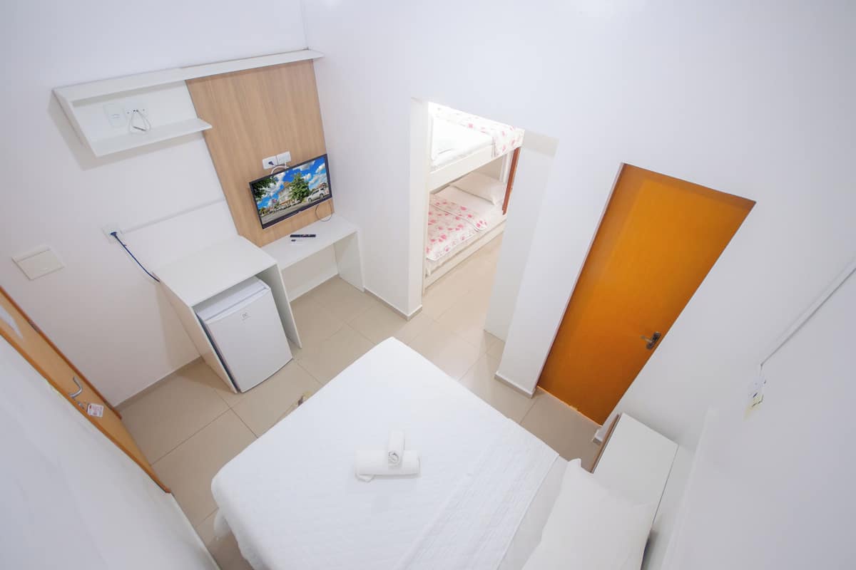 Une chambre d’hôtel avec un lit, un bureau avec un ordinateur, une télévision et un lit superposé.
