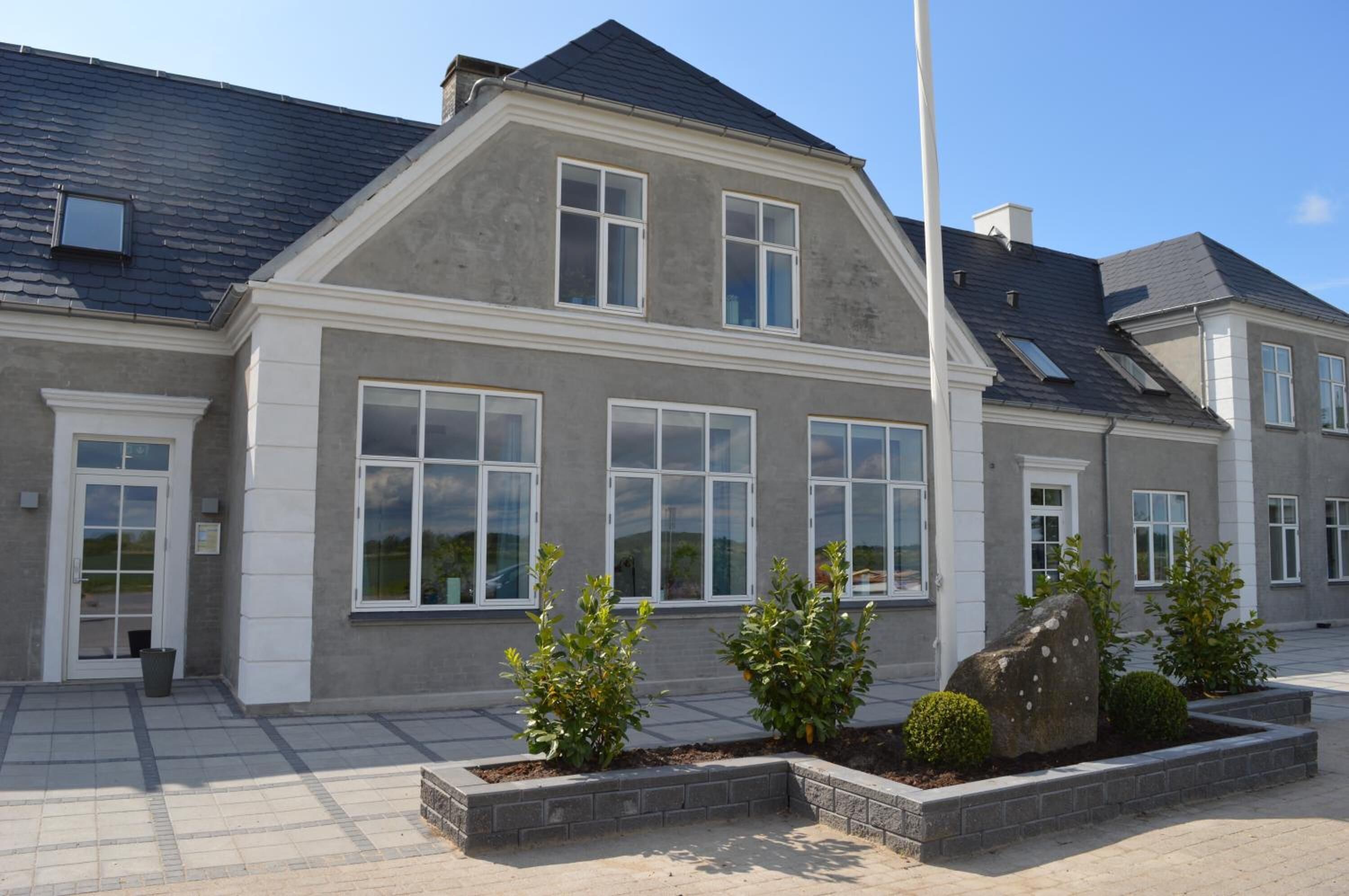 Et toetagers hus med en grå facade, store vinduer og et skråt tag.