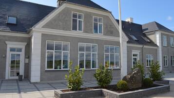 Et toetagers hus med en grå facade, store vinduer og et skråt tag.
