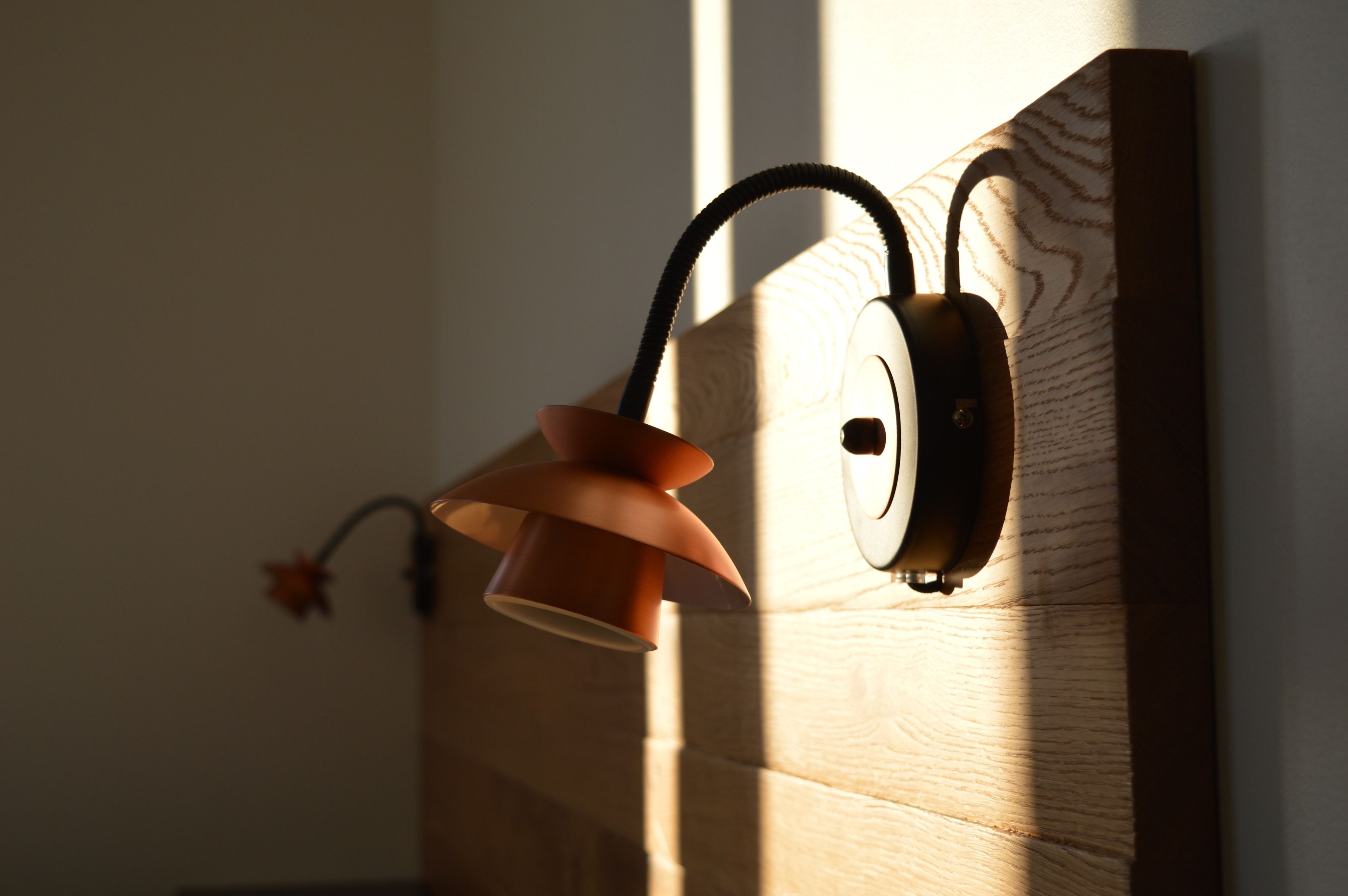 A wall-mounted lamp with a curved design, a cord, and a switch.