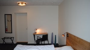 A hotel room with a bed, a desk, a chair, and a lamp. - Femhøj (Jægerspris)