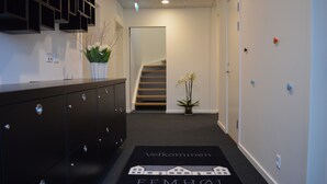 A hallway with a black dresser, a potted plant, a staircase, and a welcome mat with text. - Femhøj (Jægerspris)