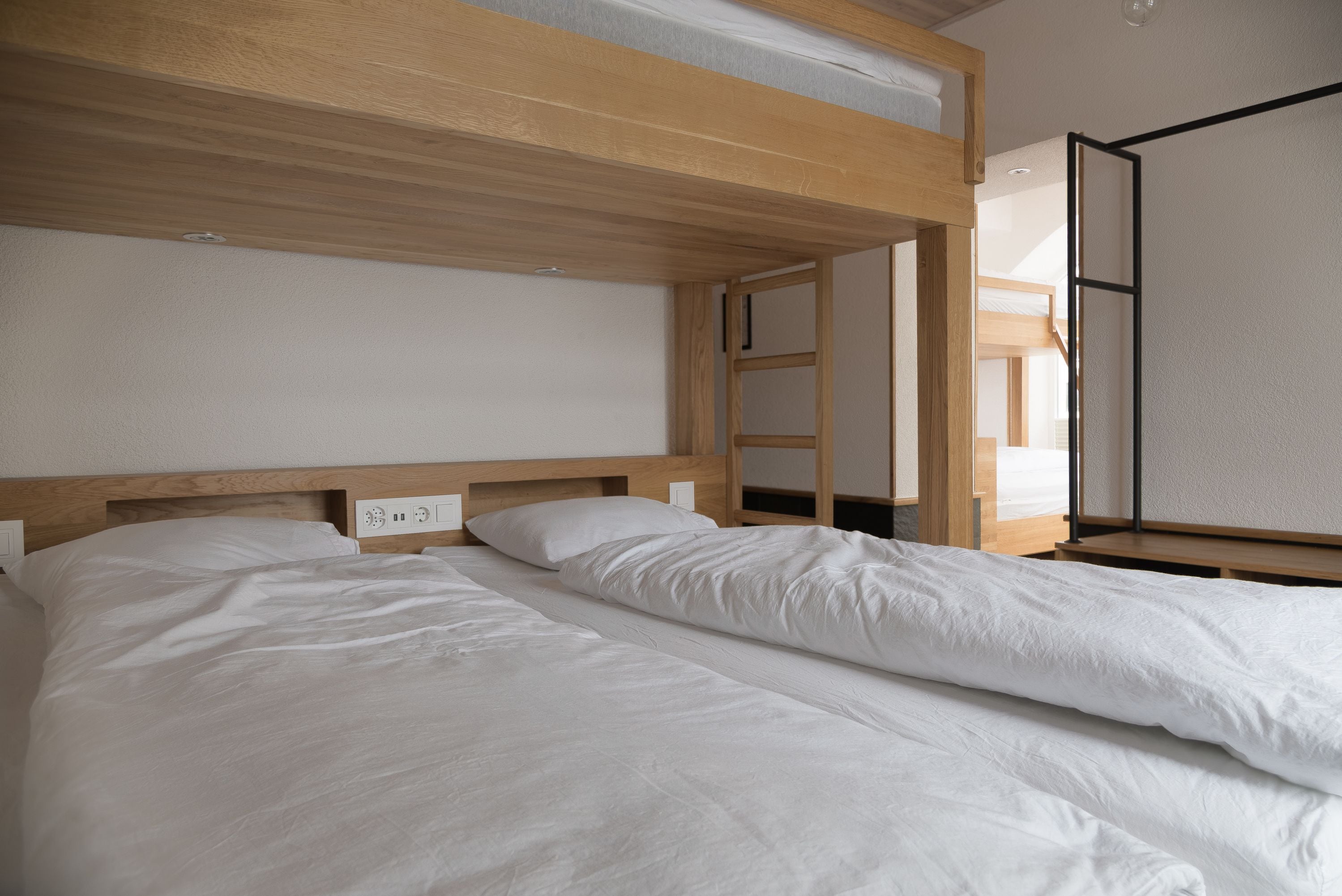 A bedroom with two beds, wooden headboards, and a window with a view.