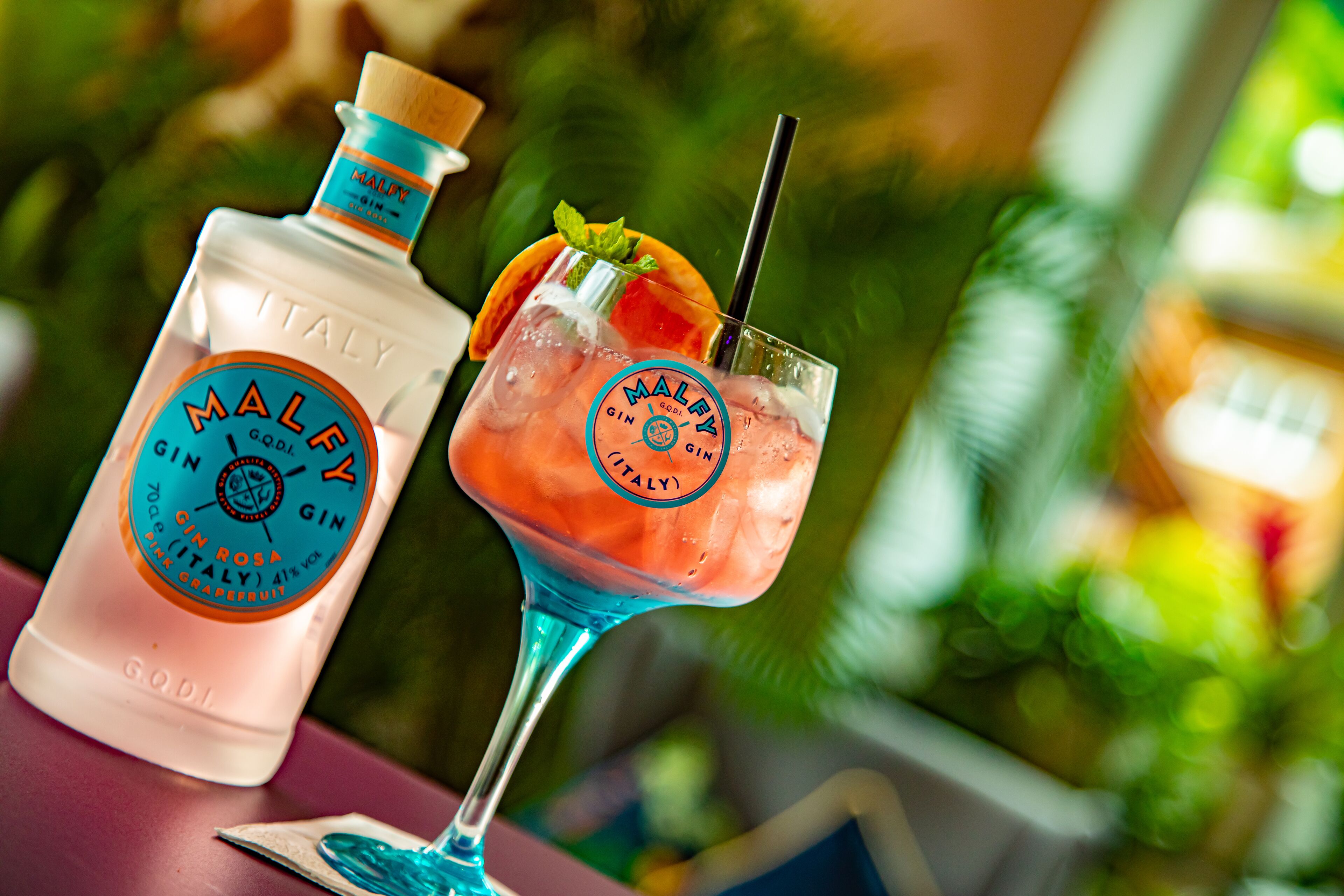 A bottle of Maley Gin and a cocktail glass with a straw.