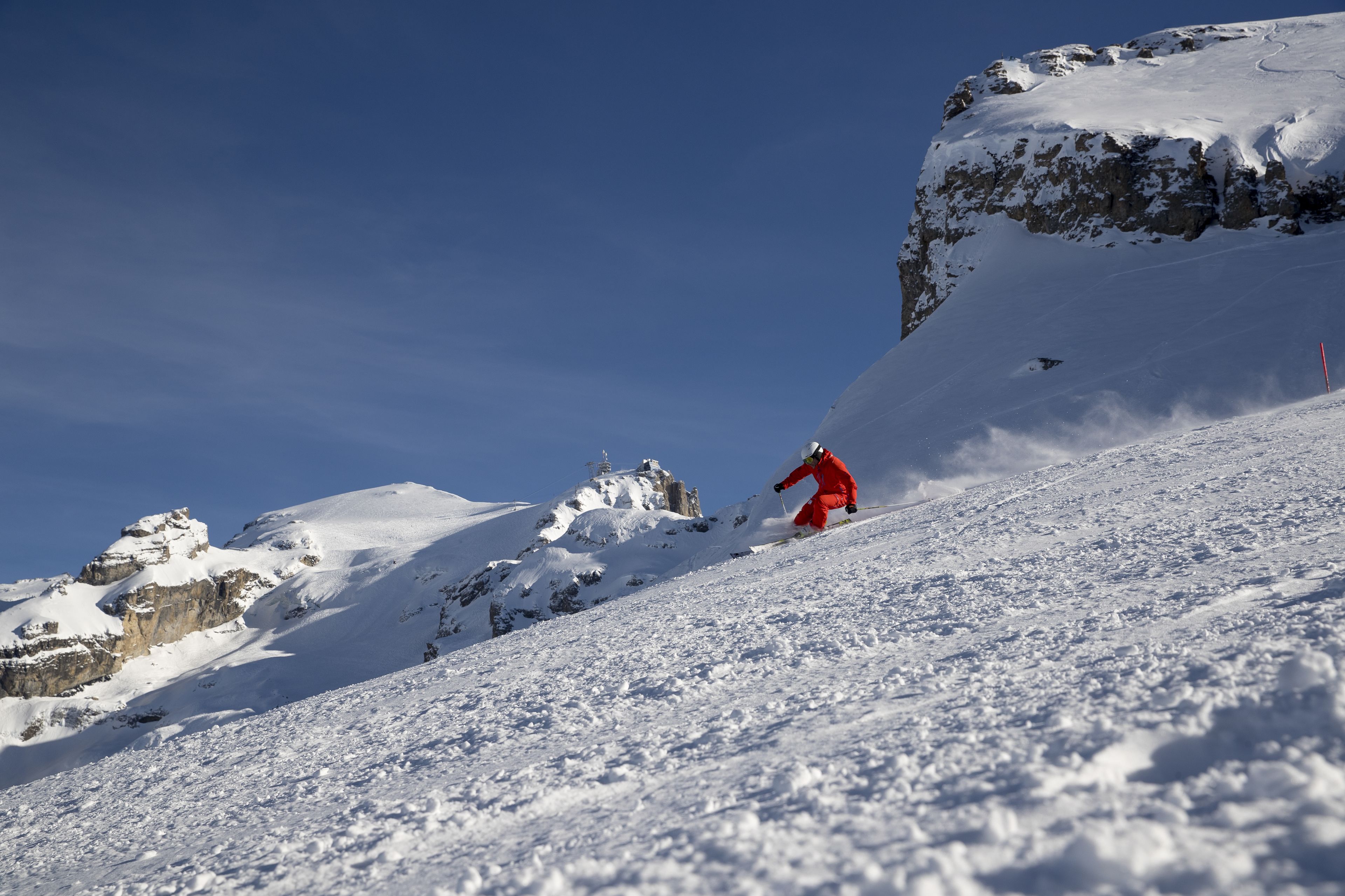 Pendio innevato di montagna con uno sciatore con abbigliamento rosso.