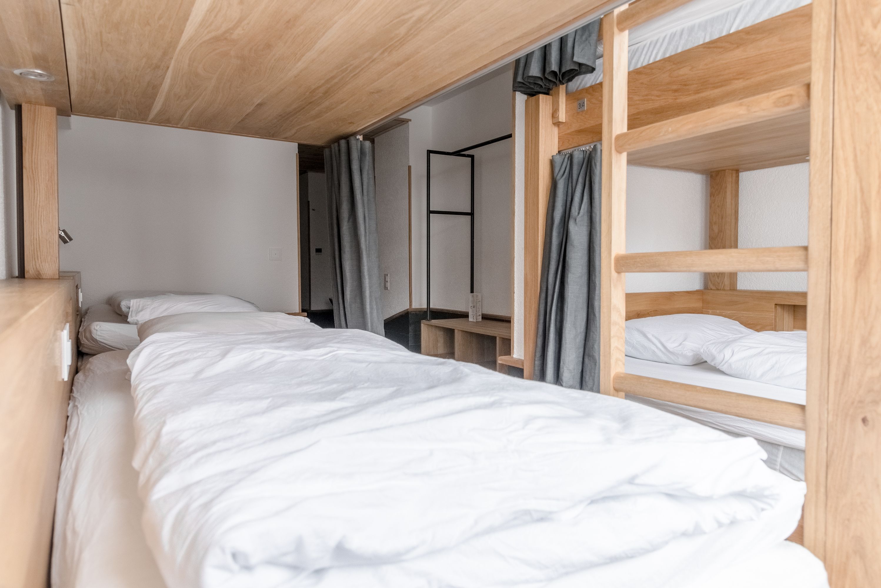 A bunk bed room with a wooden ceiling and a small desk.