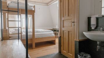 Una habitación con una cama litera, un armario de madera, un lavabo y un espejo.