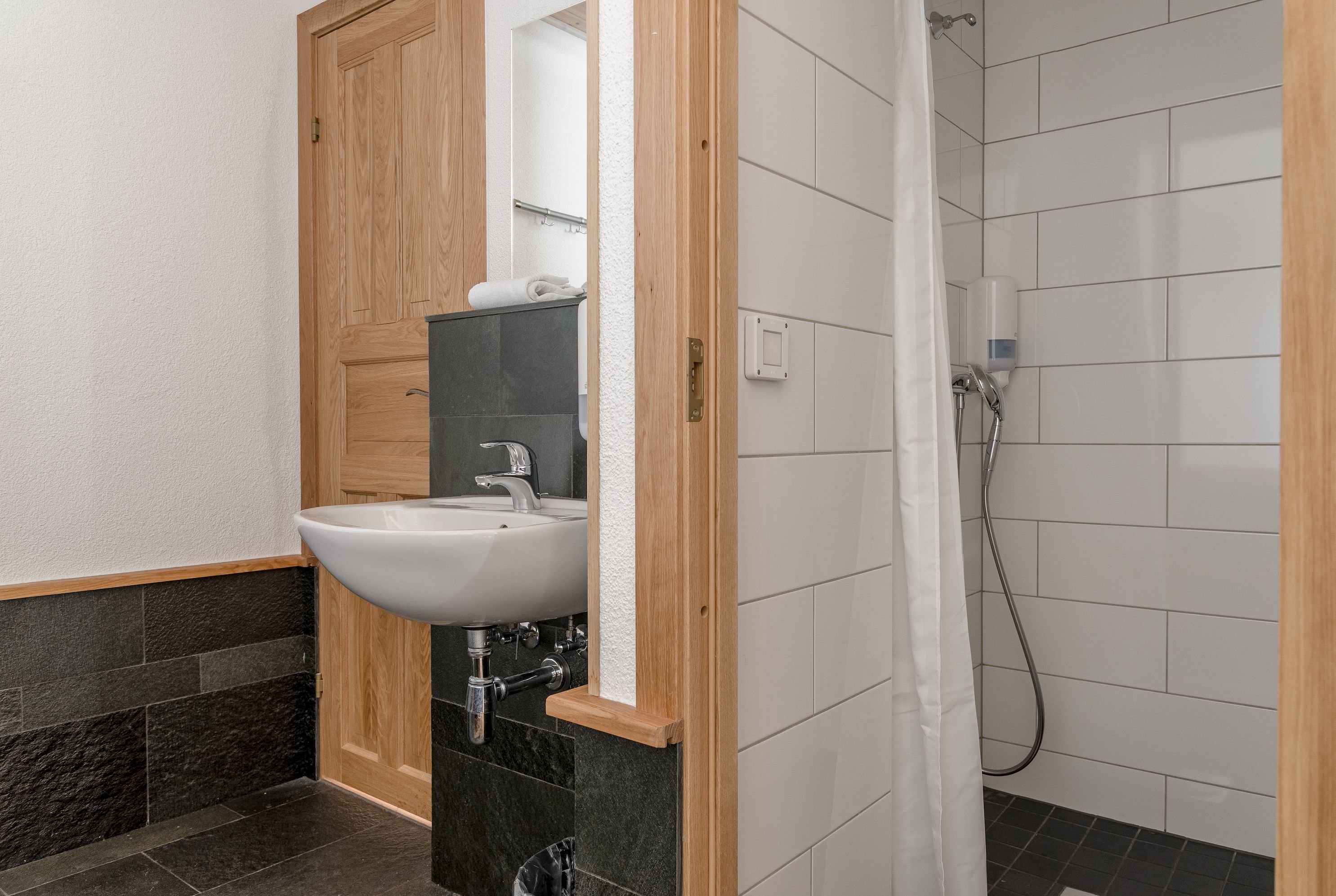 Un baño con lavabo, espejo, ducha y paredes de azulejos.