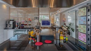 A modern kitchen with stainless steel appliances, a coffee station, and a view of the dining area. - GRAND your home with common kitchens with self check-in (Engelberg)