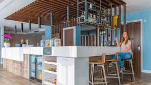 A modern kitchen with a bar area, a refrigerator stocked with snacks, and a wine rack. - Hampton by Hilton Amsterdam Centre East (Amsterdam)