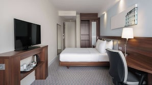 A hotel room with a bed, a TV, a desk, and a lamp. - Hampton by Hilton Amsterdam Centre East (Amsterdam)