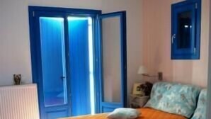 Un dormitorio con cama, mesita de noche, lámpara y ventana con cortinas azules.