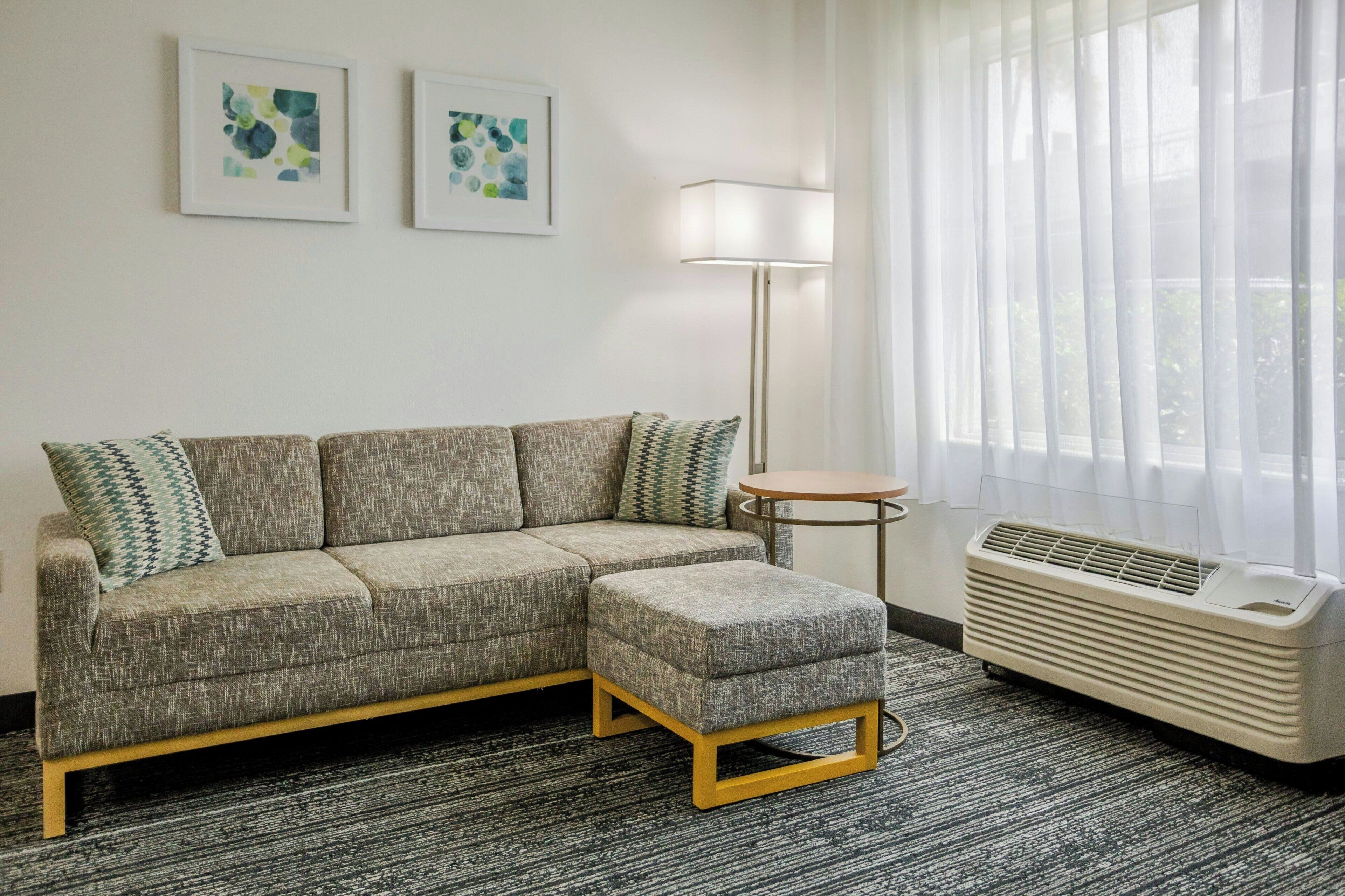 A modern living room with a grey sectional sofa, a small round table, and a standing floor lamp.
