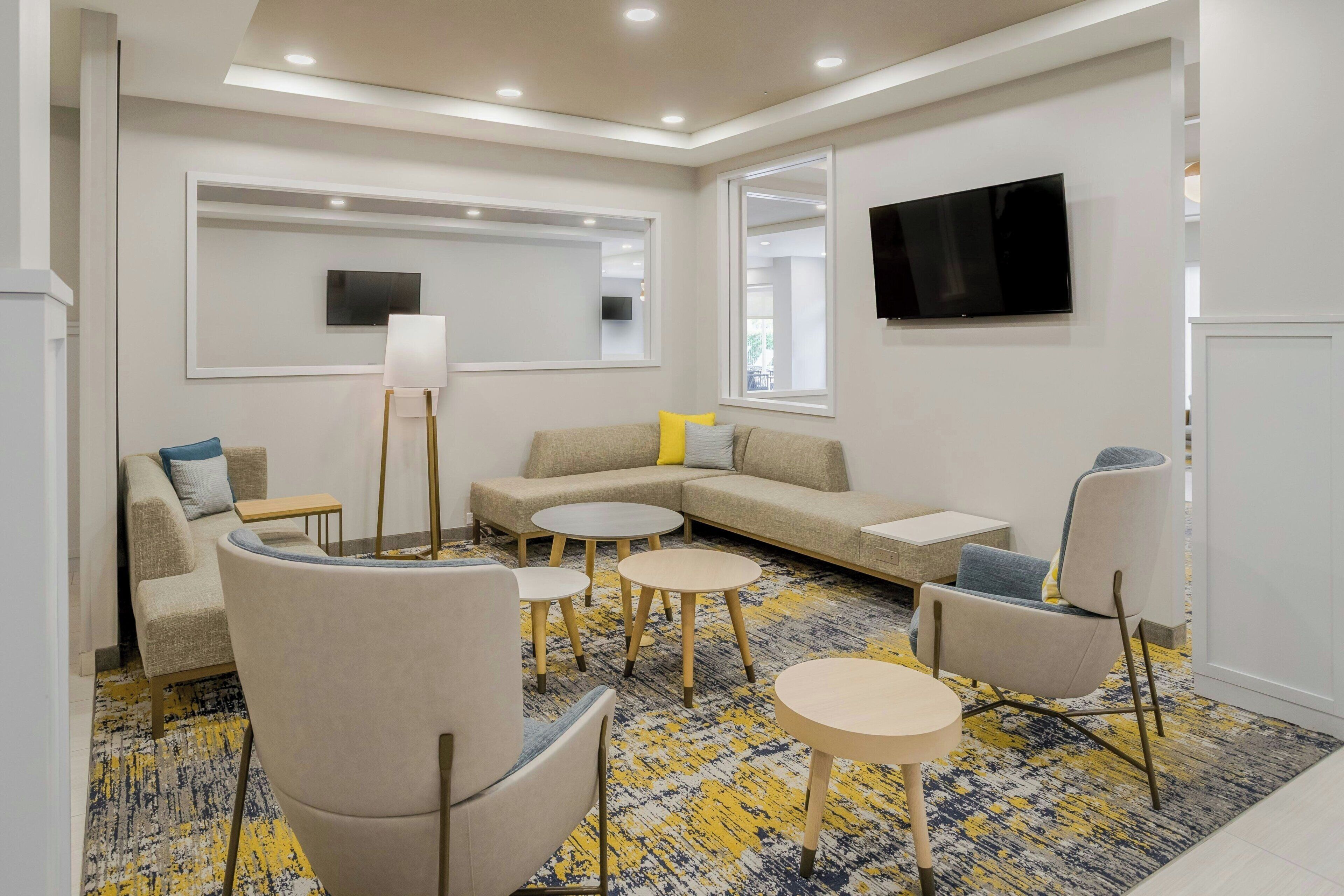 A modern living room with a sofa, armchairs, a coffee table, and a TV mounted on the wall.
