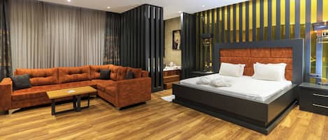 A modern bedroom with a large bed, a sofa, and a wooden floor.