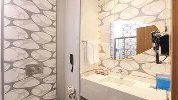 A bathroom with a modern design, featuring a patterned wall, a mirror with a wooden frame, a hairdryer, and a sink with a soap dispenser.