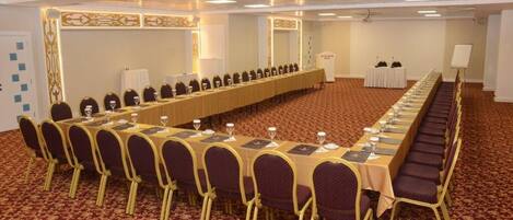 A conference room with a long table, chairs, and a carpeted floor.