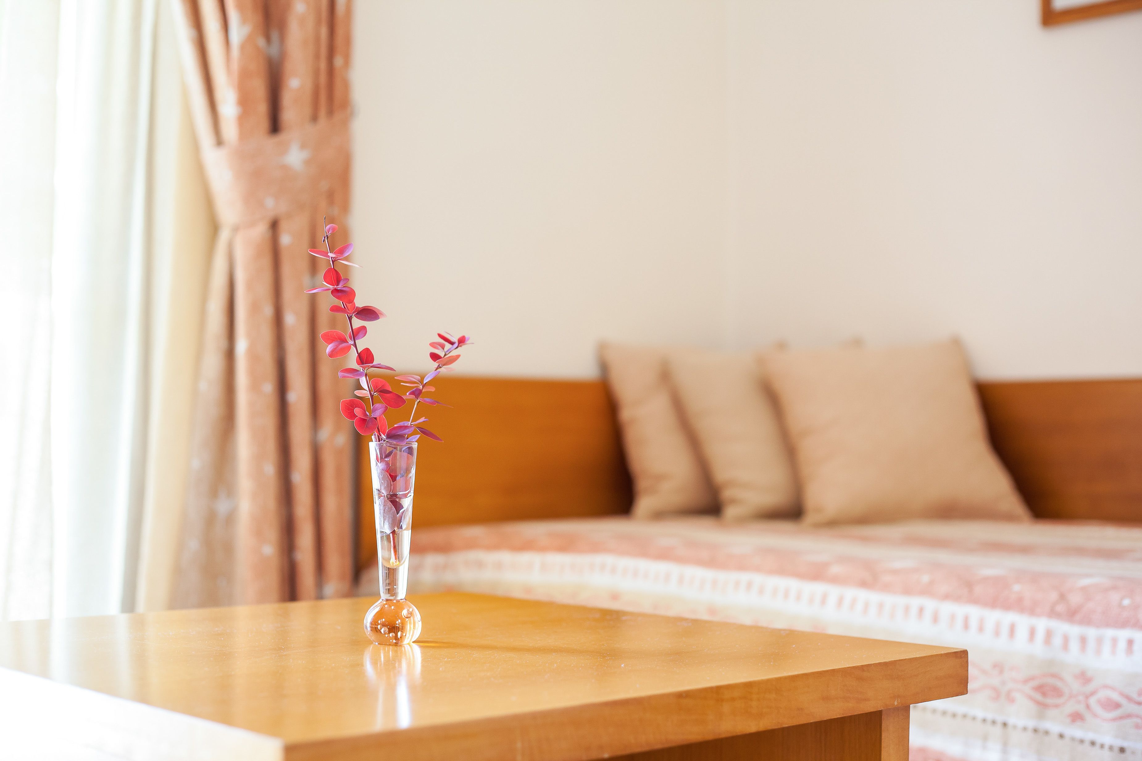 Ein Holztisch mit einer klaren Vase, die rosa Blumen enthält.