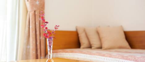 Ein Holztisch mit einer klaren Vase, die rosa Blumen enthält.