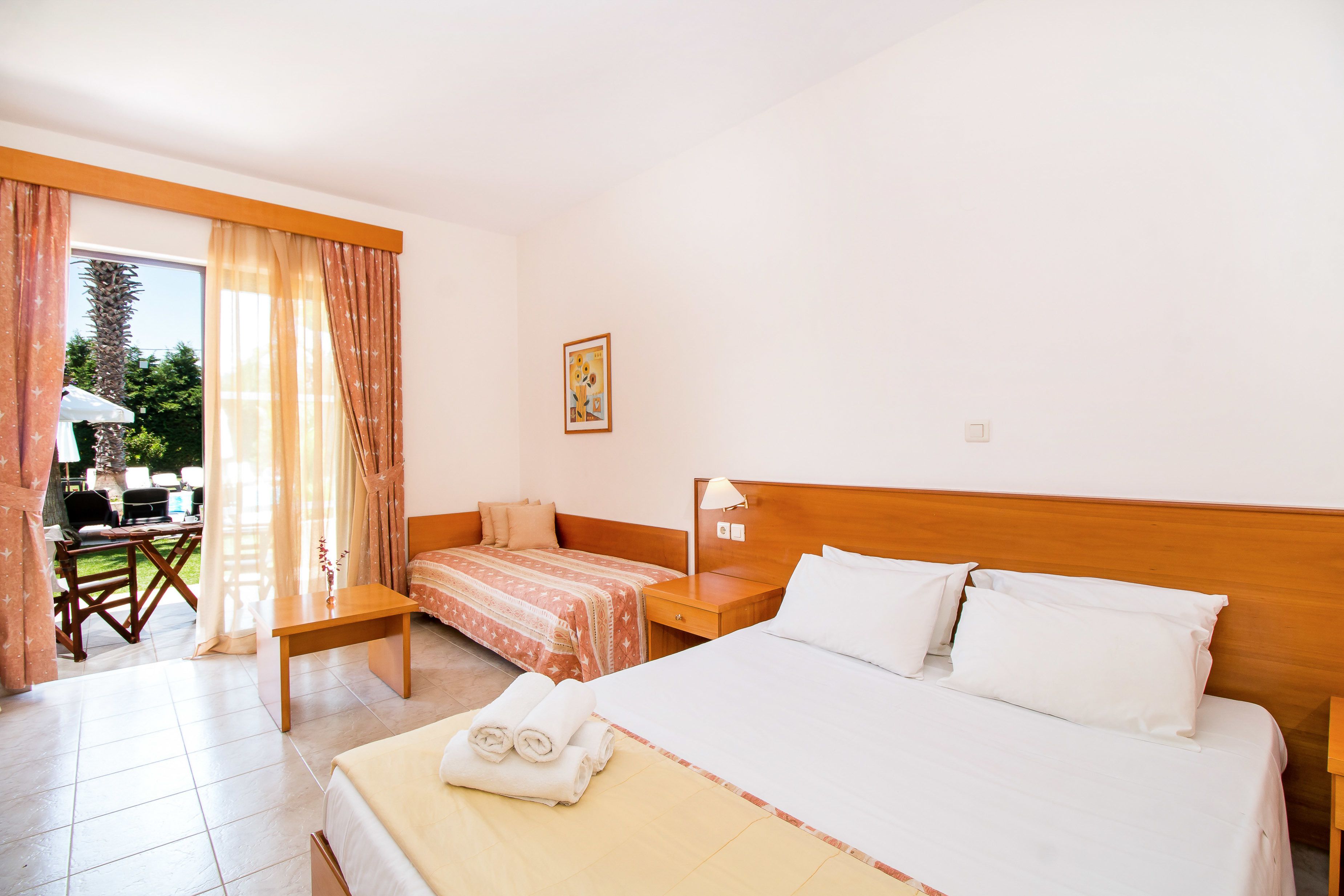 A hotel room with a large bed, a smaller bed, a desk, and a chair.
