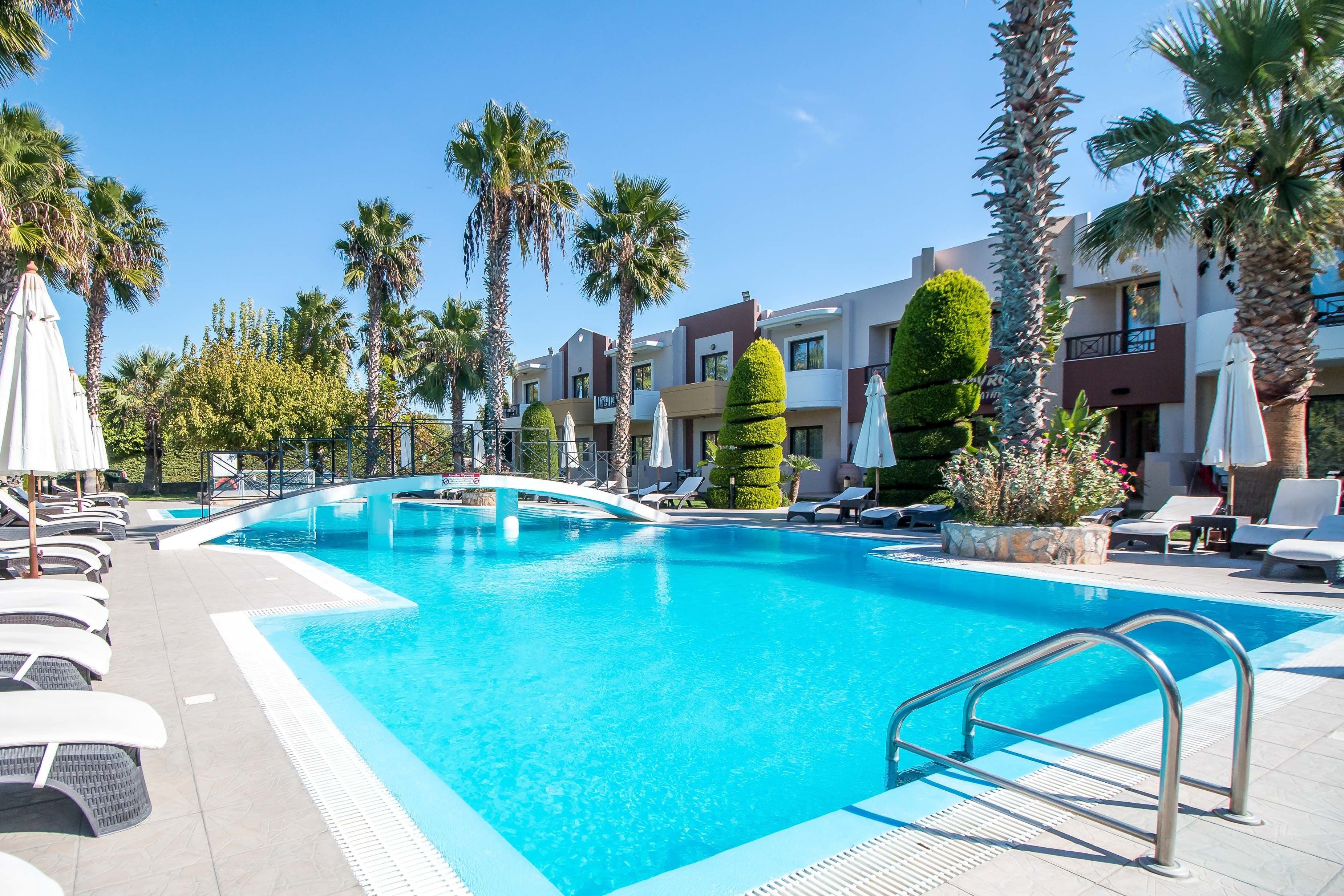 A swimming pool with lounge chairs and palm trees.