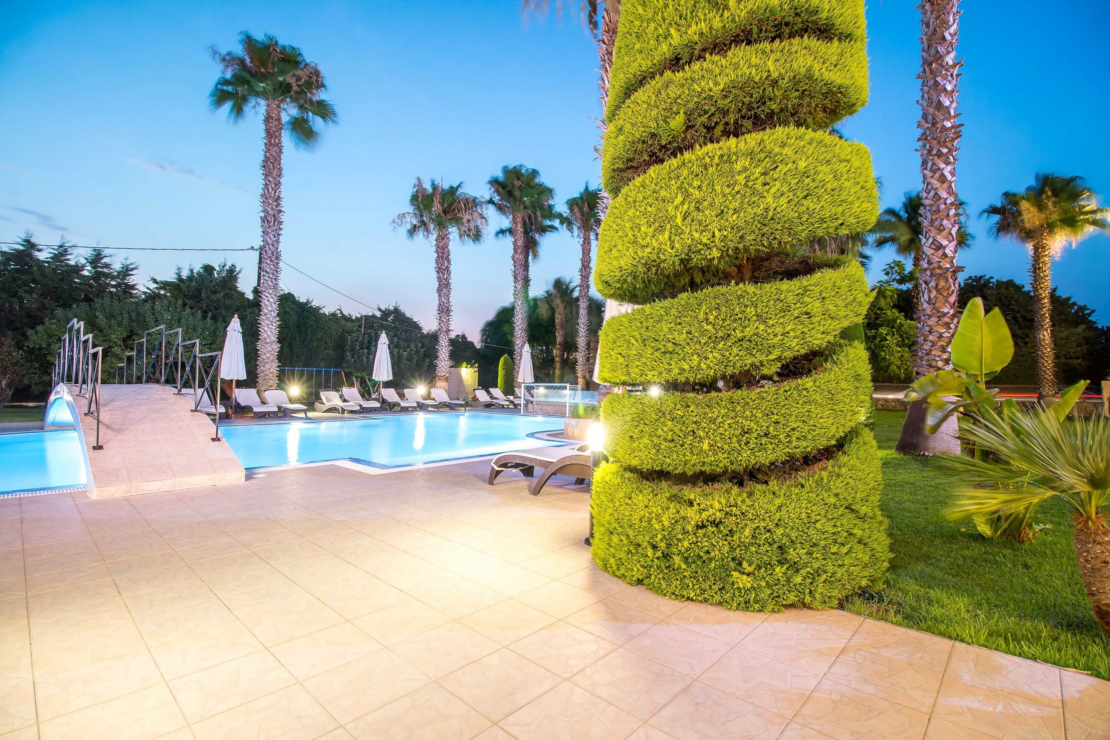 Ein Poolbereich mit Liegestühlen und einem gepflegten Garten mit Palmen.