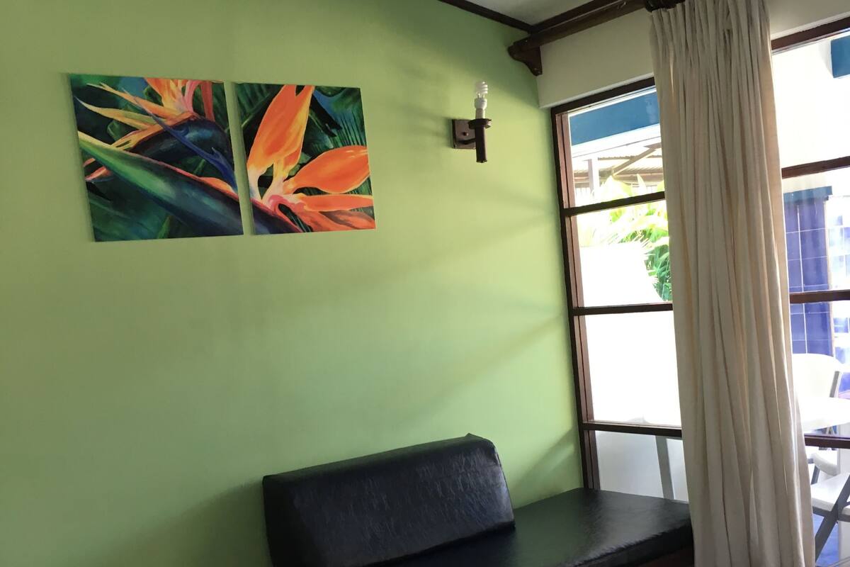A room with a green wall, a bench, a massage table, and a window with curtains.